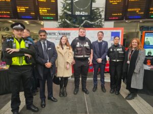 Councillors and ASB officers posing for a photo in front of the pledge wall during White Ribbon Day